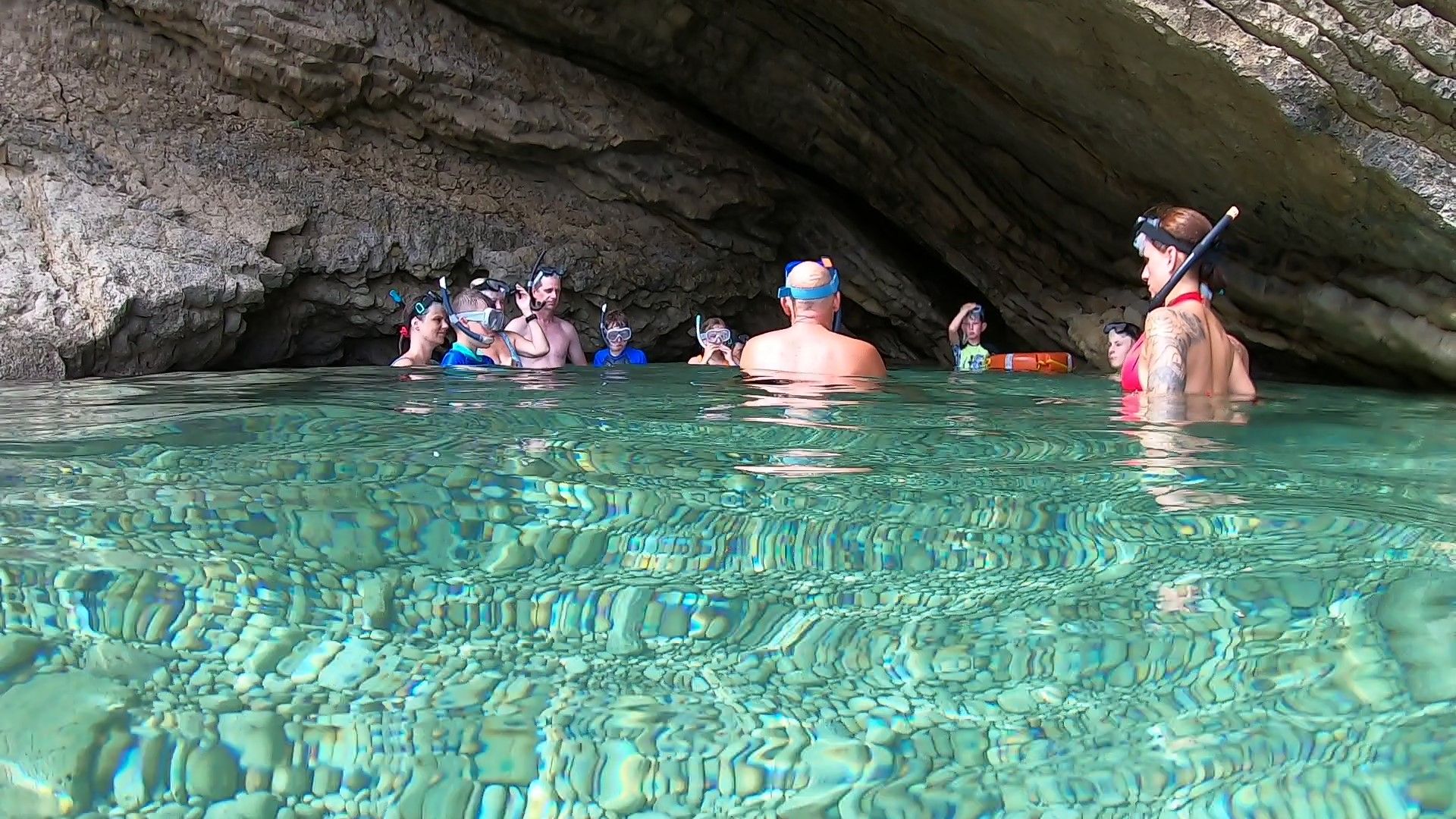 Grupo de esnorkelistas principiantes tomandose un descanso de pie, con el agua hasta la cintura, durante la excursion familiar en barco o family boat trip de Meet the Sea en Ibiza