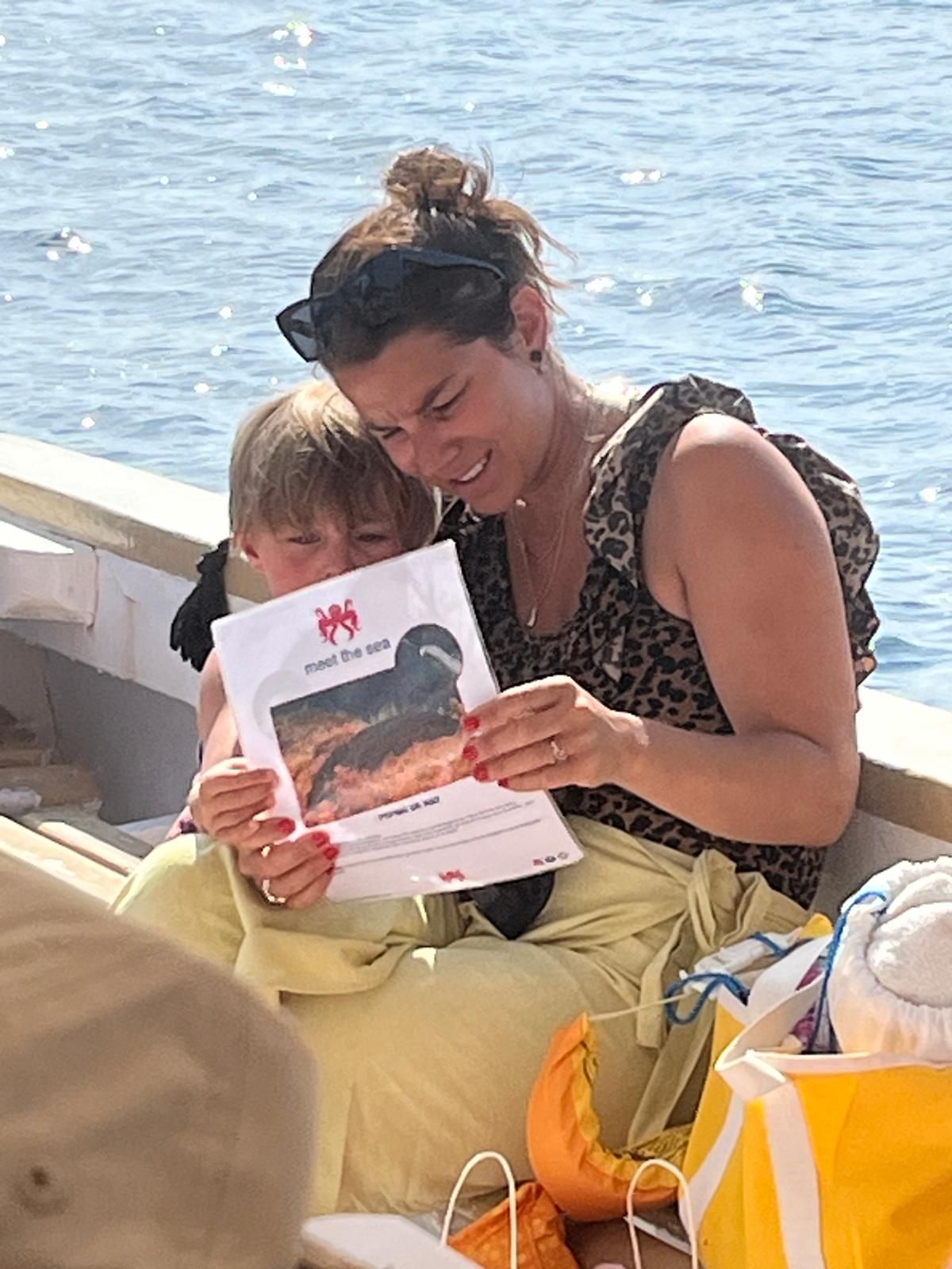 Imagen de una madre y su hijo leyendo uno de los pdf de Meet the Sea sobre especies del mar de Ibiza a bordo de nuestra excursion familiar en barco o Family Boat trip