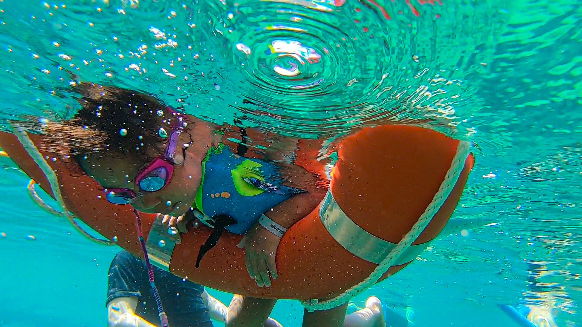 Niño en el mar con gafas, chaleco y salvavidas observando el fondo marino durante la excursión familiar en barco o Family boat trip de Meet the Sea en Ibiza