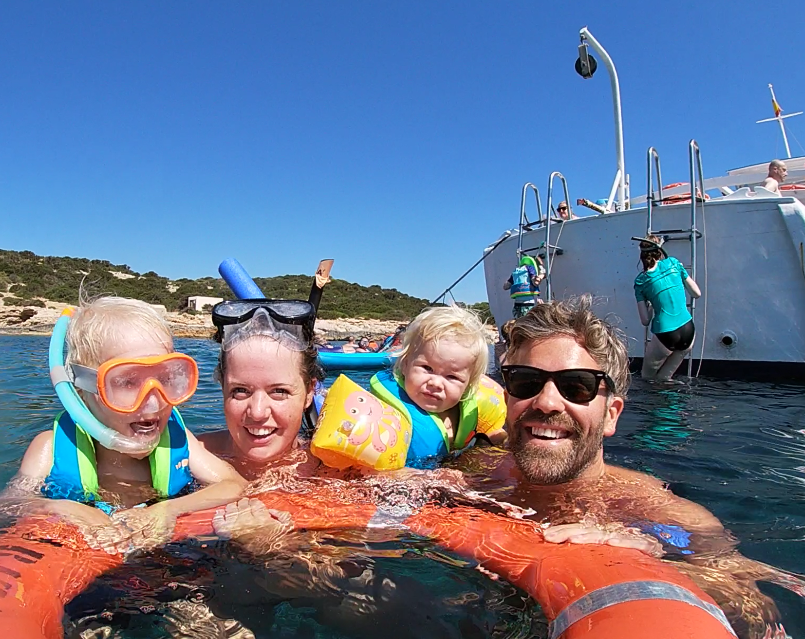 Excursión familiar en barco de Meet the Sea. Imagen de dos bebés de 1 y 3 años con salvavidas y padres acompañándoles en nuestro tour guiado de esnorquel